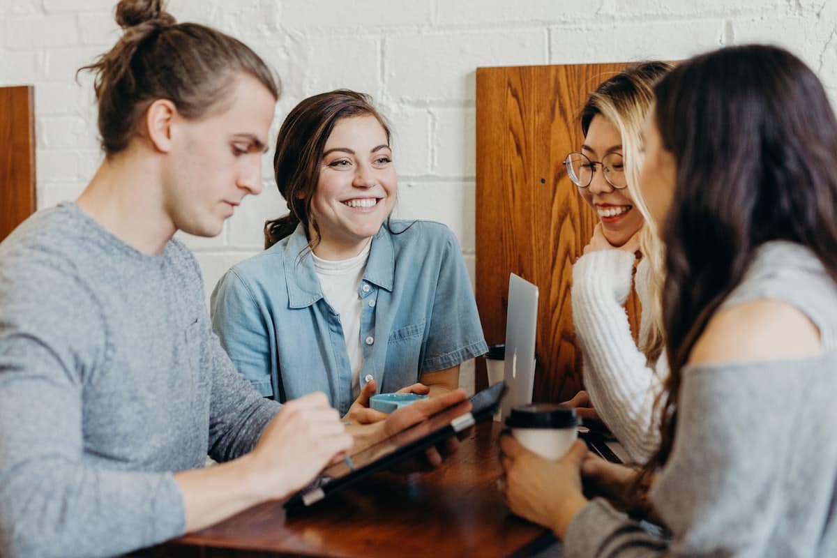 Cuatro estudiantes conversando y riendo alrededor de una mesa durante una sesión de conversación